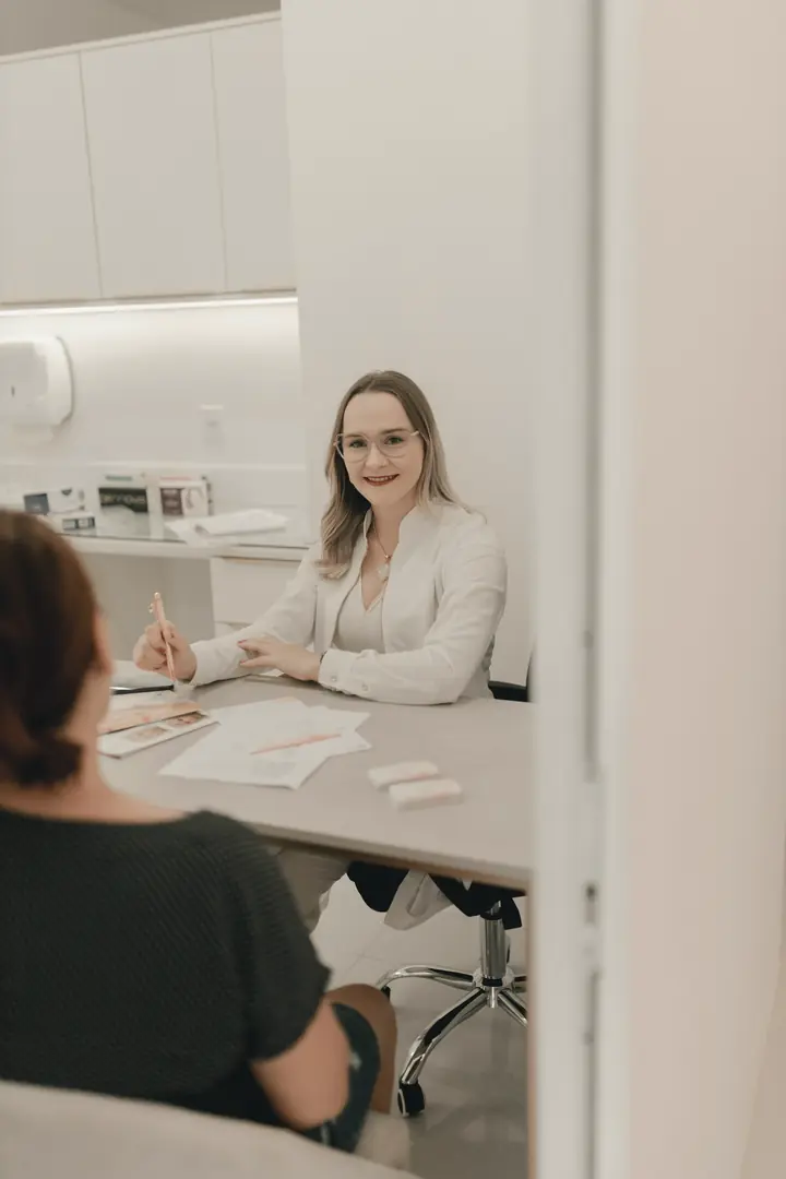 A doctor talking with a patient across a desk in a bright clinic