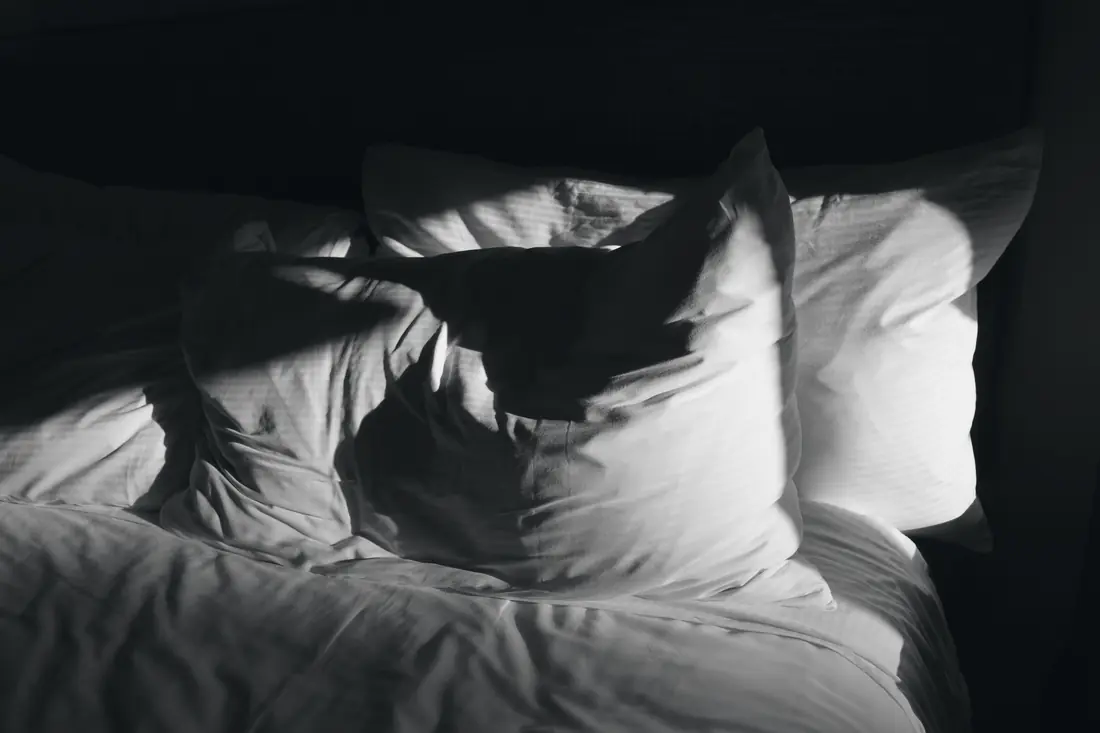 Pillows on a bed in low light, black and white
