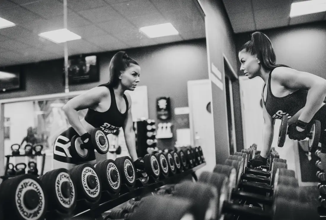 Two athletes training with dumbbells in a studio, black and white